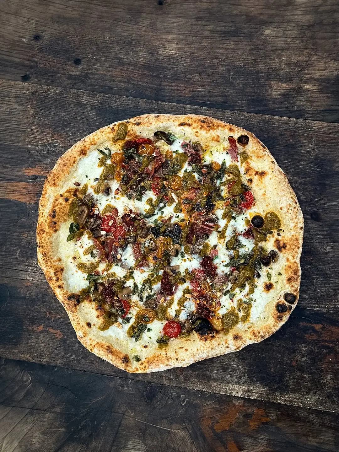 Neapolitanische Gourmetpizza mit Pesto, Tomaten und gut gebackenem Rand